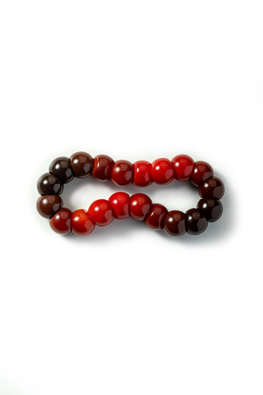 Beaded bracelet with alternating red and brown beads on a white background