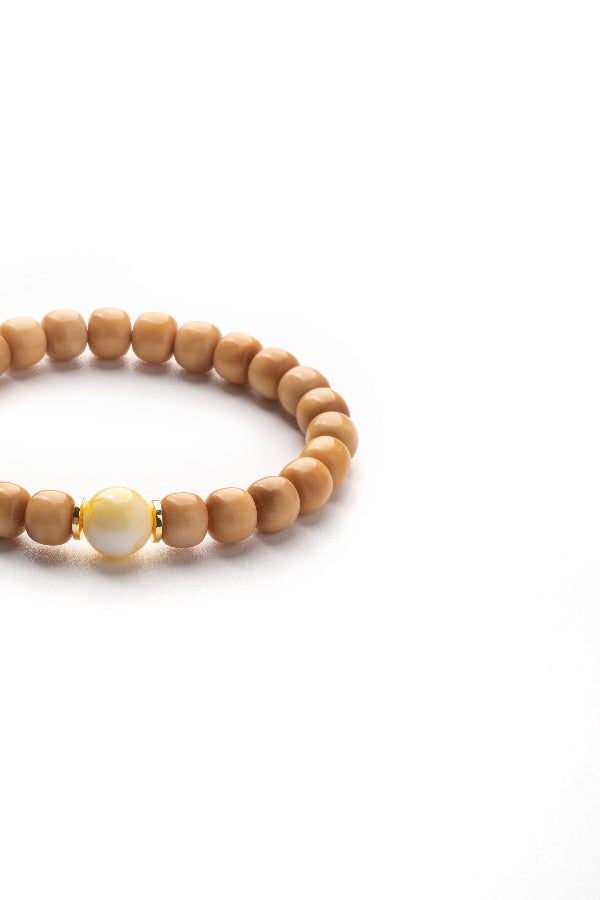 Wooden beaded bracelet with a single white bead on a white background